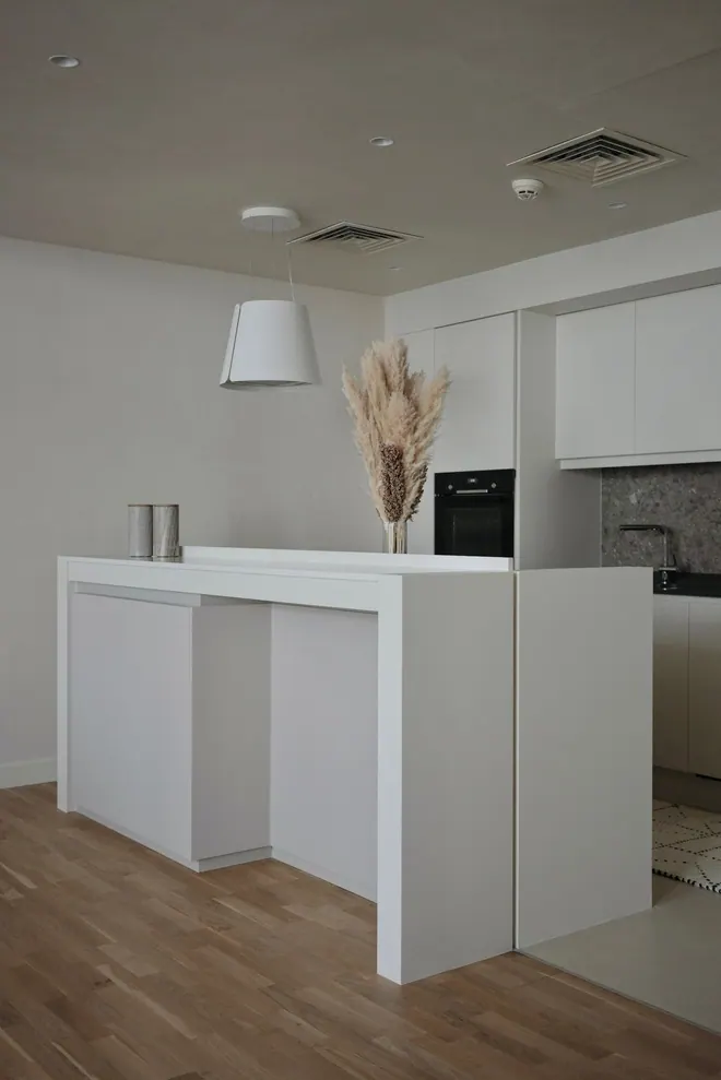 White handleless kitchen with a waterfall island and pampas grass