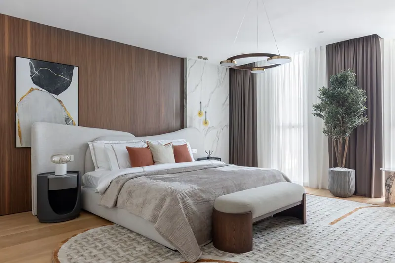 Master bedroom with walnut and marble wall panels, a wave-shaped headboard and a ring chandelier