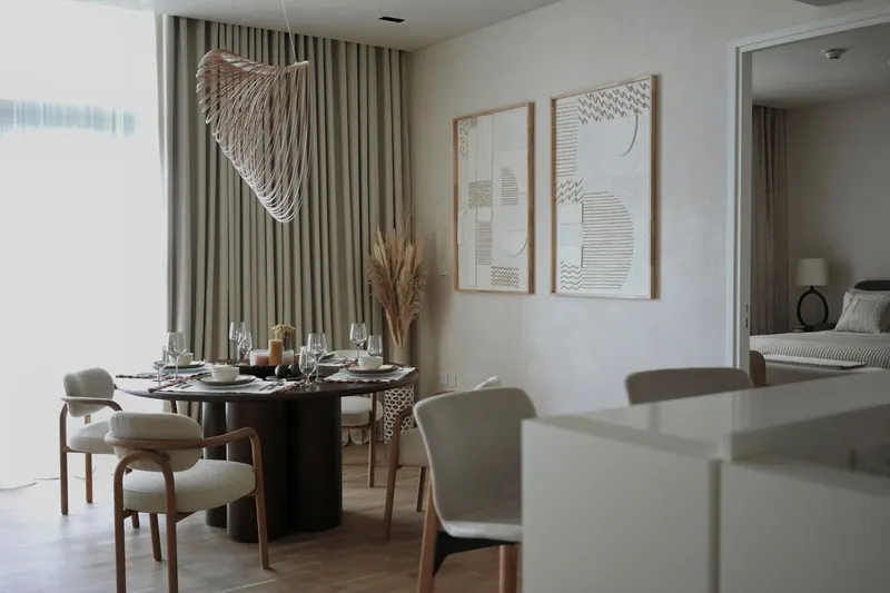 Dining area with a round table, bouclé chairs and a sculptural pendant in a Bluewaters apartment