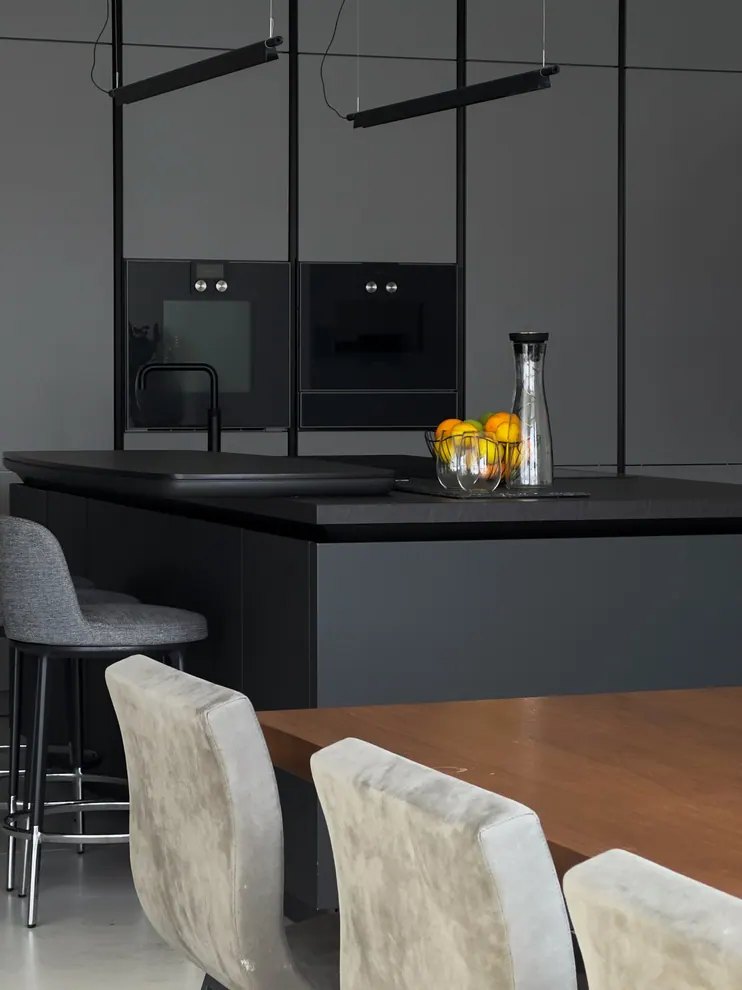 Matt graphite kitchen with built-in ovens, an island and a wooden breakfast table
