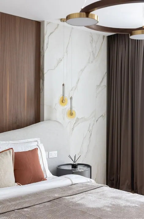 Bedside with gold-veined marble wall, walnut panel and amber glass pendants