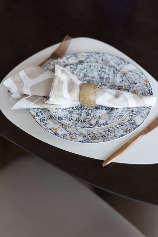 Table setting with patterned porcelain, a linen napkin and copper cutlery