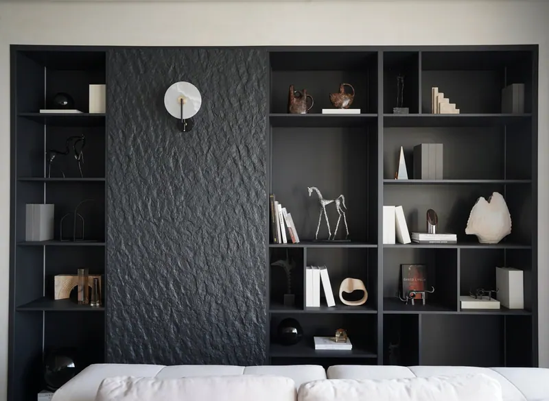 Built-in black shelving wall with a textured stone panel in a residence at Atlantis The Royal
