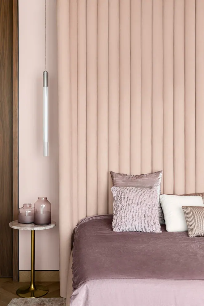Channel-tufted blush velvet headboard wall with a glass tube pendant and a marble side table