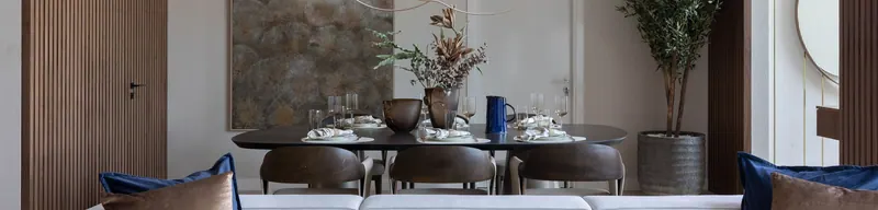Dining room with a dark oval table, walnut chairs and a slatted walnut door